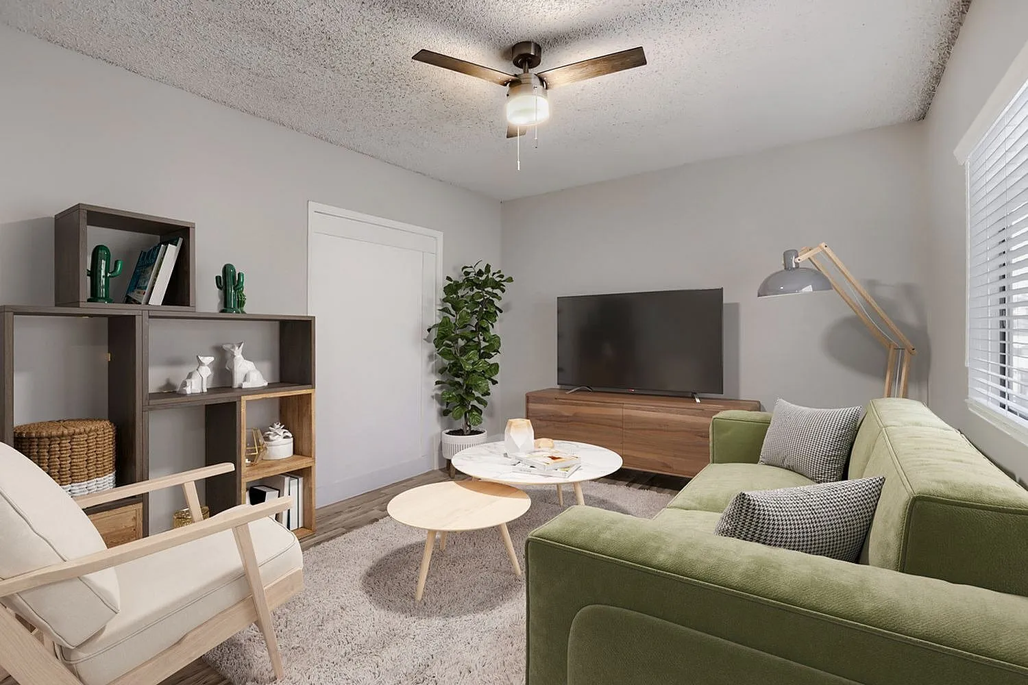 Living room, green upholstered sofa, wood-style plank flooring, ceiling fan, wall-mounted television