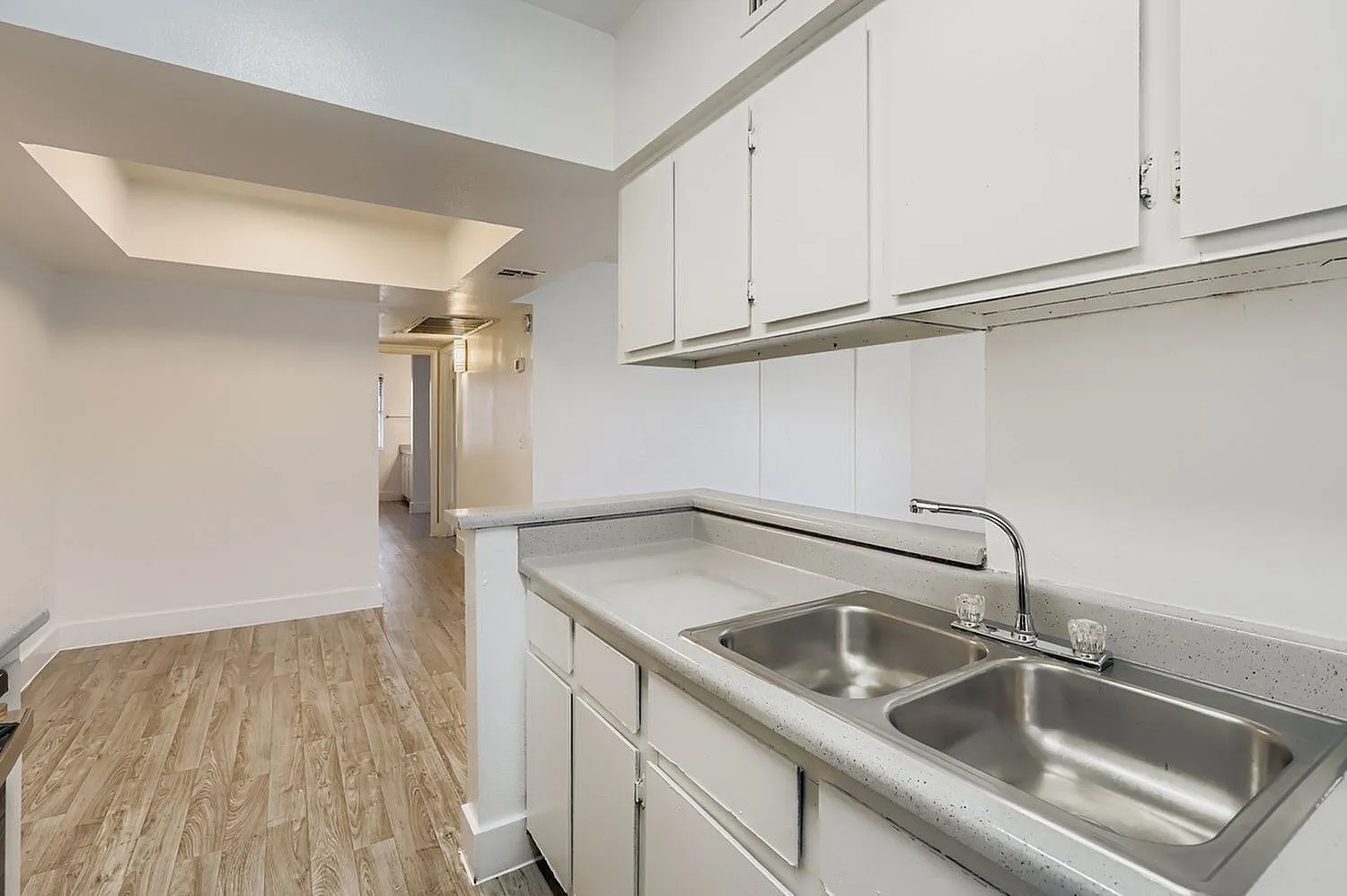 Kitchen, white shaker cabinetry, stainless steel double sink, wood-style plank flooring
