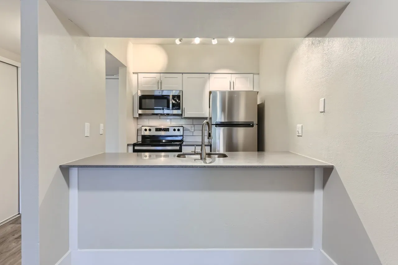Kitchen, white cabinetry, gray quartz countertops, stainless steel appliances, microwave, island seating