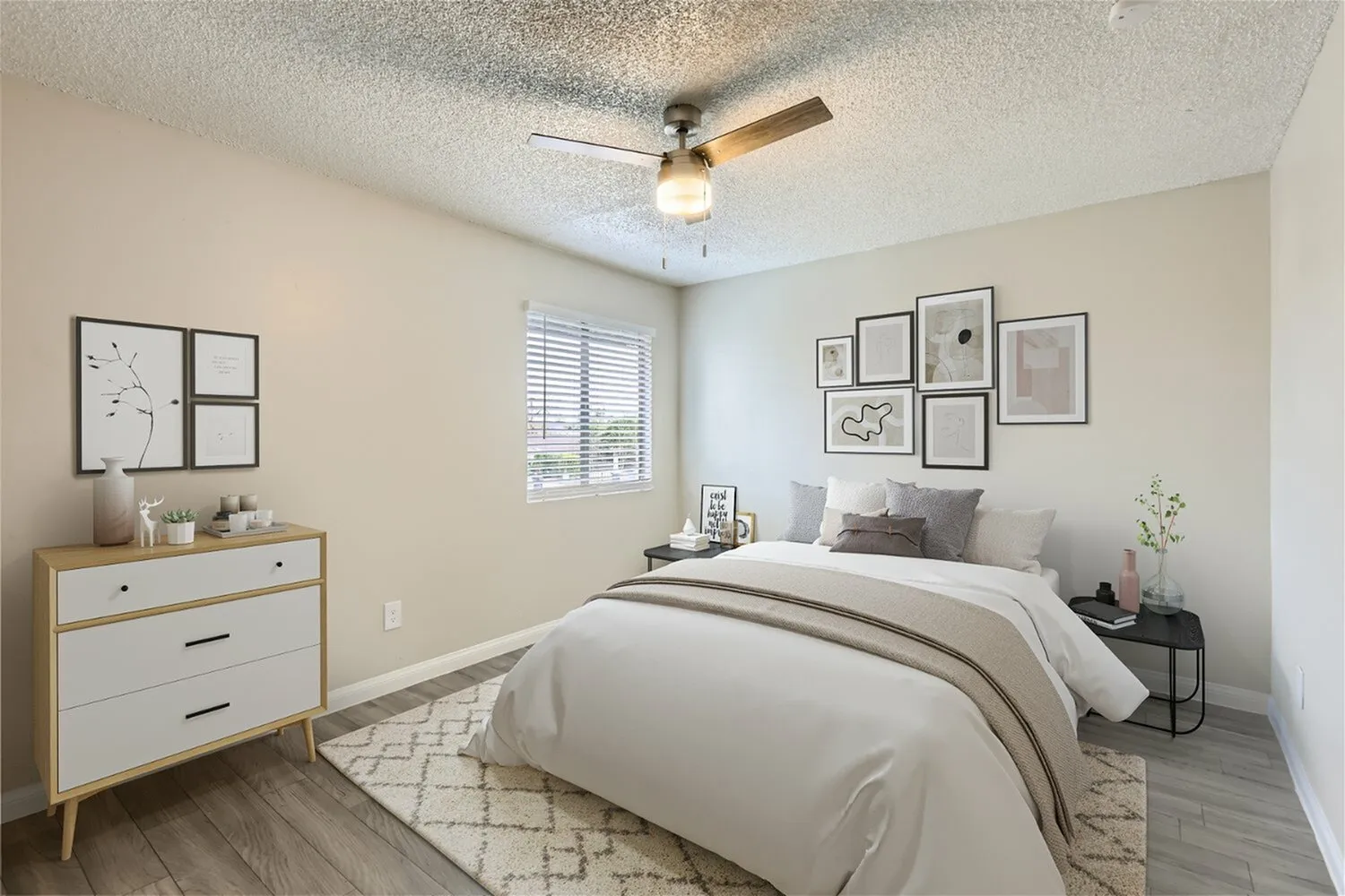 Primary bedroom with wood-style plank flooring, ceiling fan with light, framed artwork