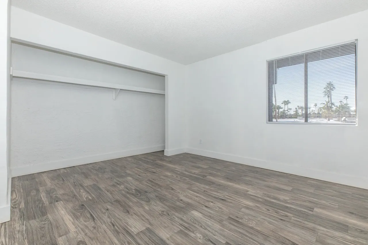 Bedroom, wood-style plank flooring, large closet, window with blinds, white walls