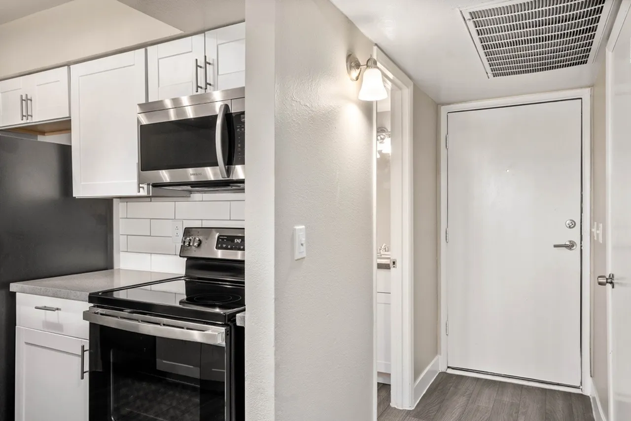 Kitchen, white shaker cabinetry, stainless steel appliances, subway tile backsplash, wood-style plank flooring