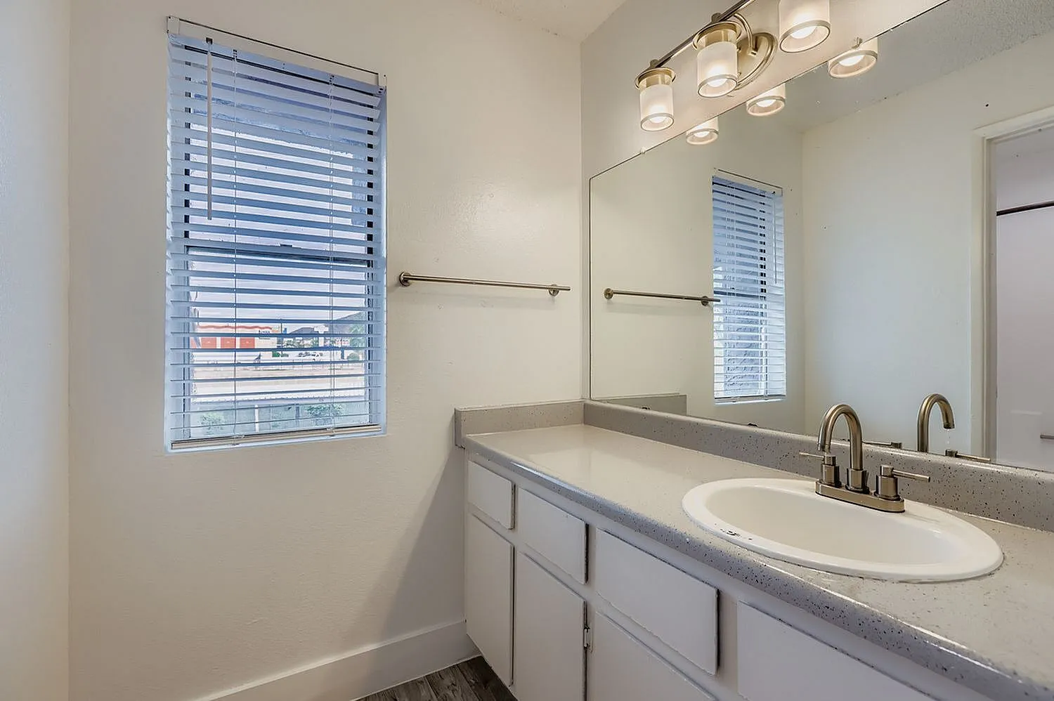Primary bathroom, white cabinetry, gray countertops, oval sink, brass fixtures