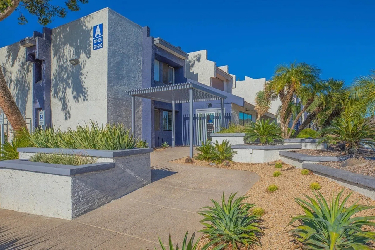 Exterior courtyard, blue and white modern architecture, desert landscaping with palm trees, gravel and pavers