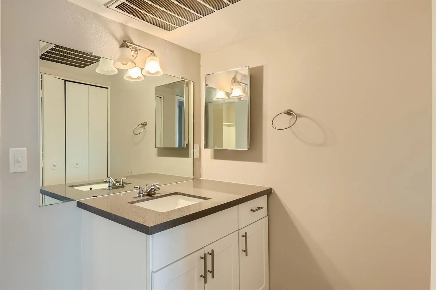 Primary bathroom, dual mirrors, quartz countertops, white cabinetry, ceiling lighting fixtures