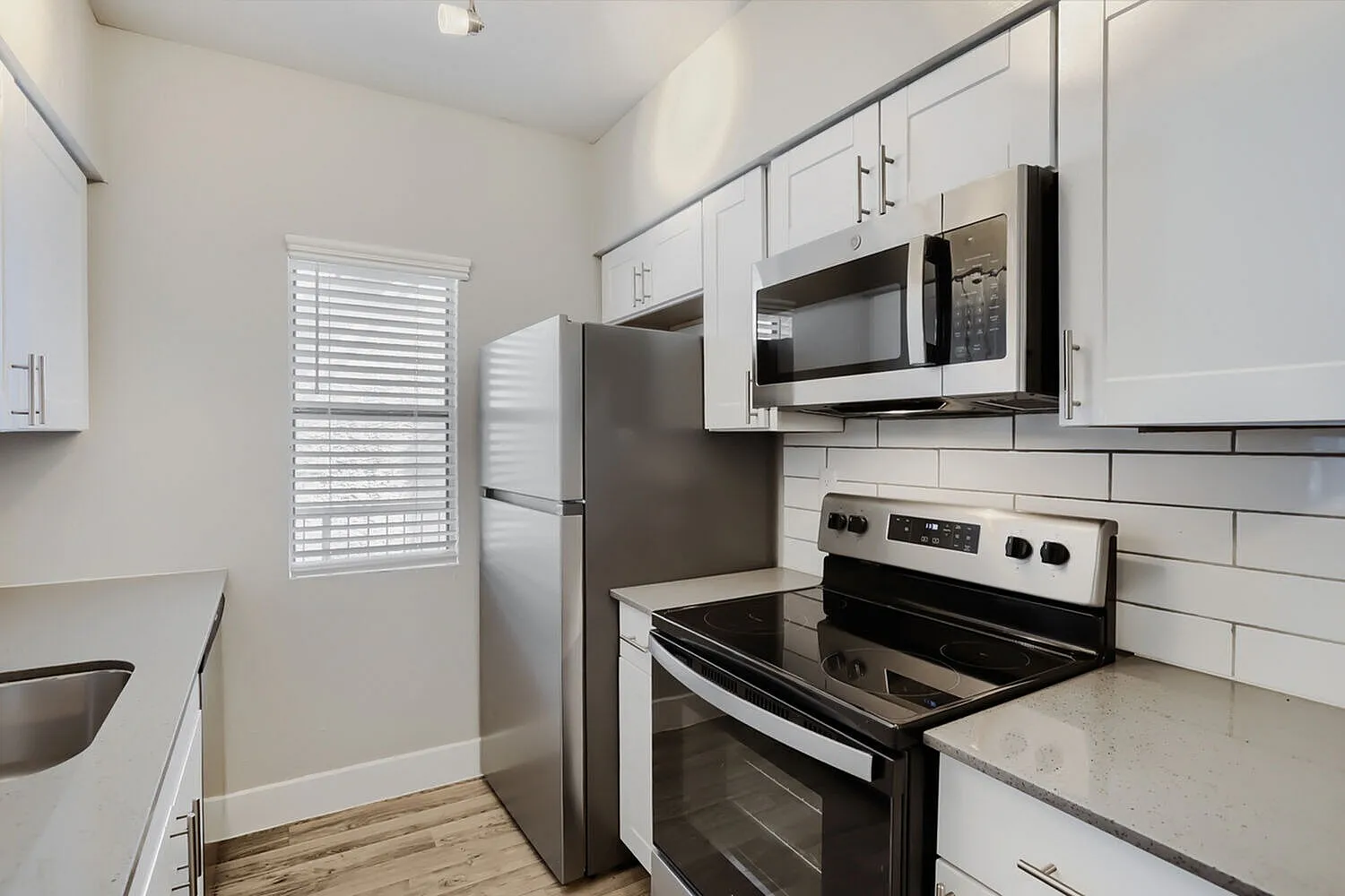 Kitchen, white shaker cabinetry, quartz countertops, stainless steel appliances, wood-style plank flooring