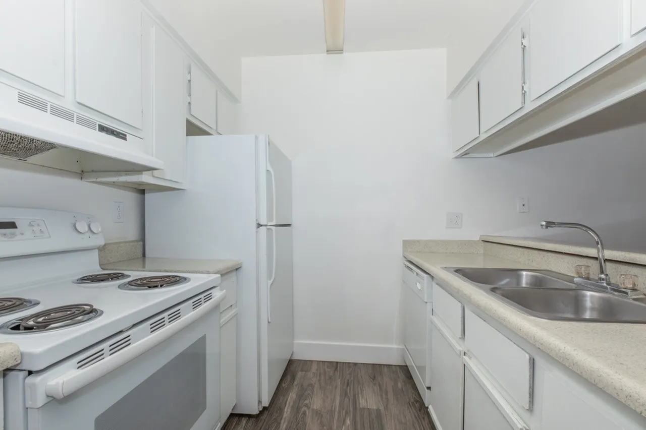 Kitchen, white cabinetry, stainless sink, gas range, refrigerator, wood-style plank flooring