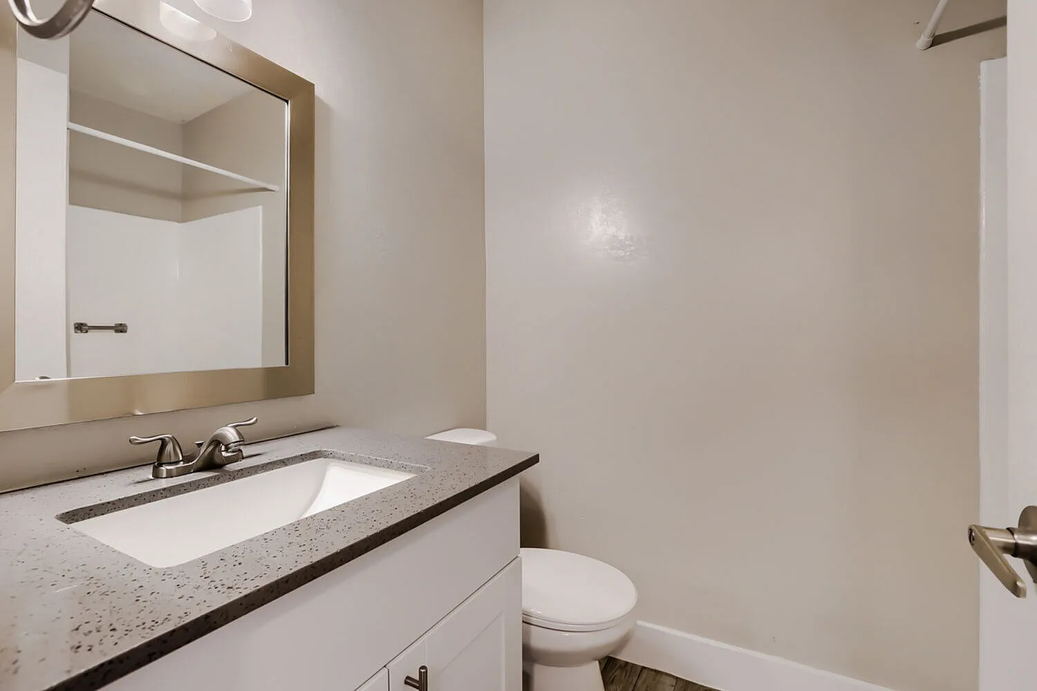 Bathroom, speckled countertops, white cabinetry, framed mirror, chrome fixtures
