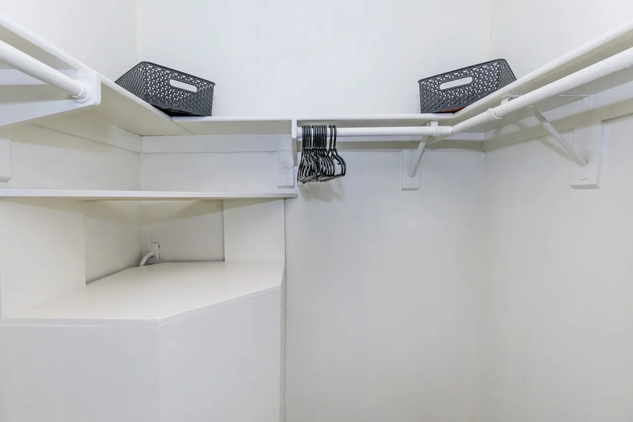 Walk-in closet, white shelving, hanging rod, storage baskets, built-in shelves