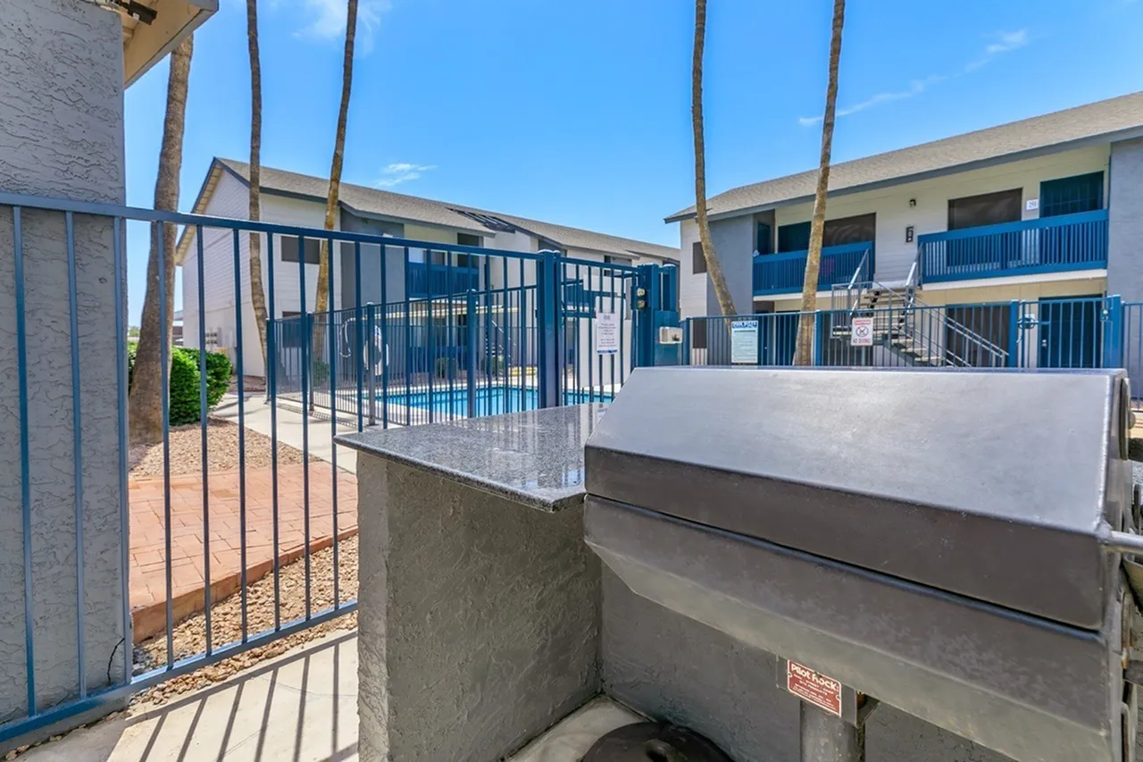 Courtyard with concrete planter, metal railing, palm trees, residential buildings with blue balconies