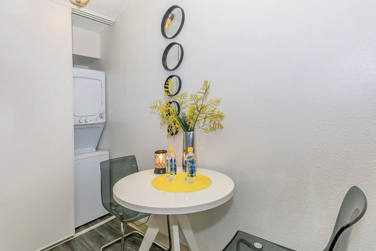Round white table, green chairs, yellow flower vase, stacked decorative rings, laundry appliances