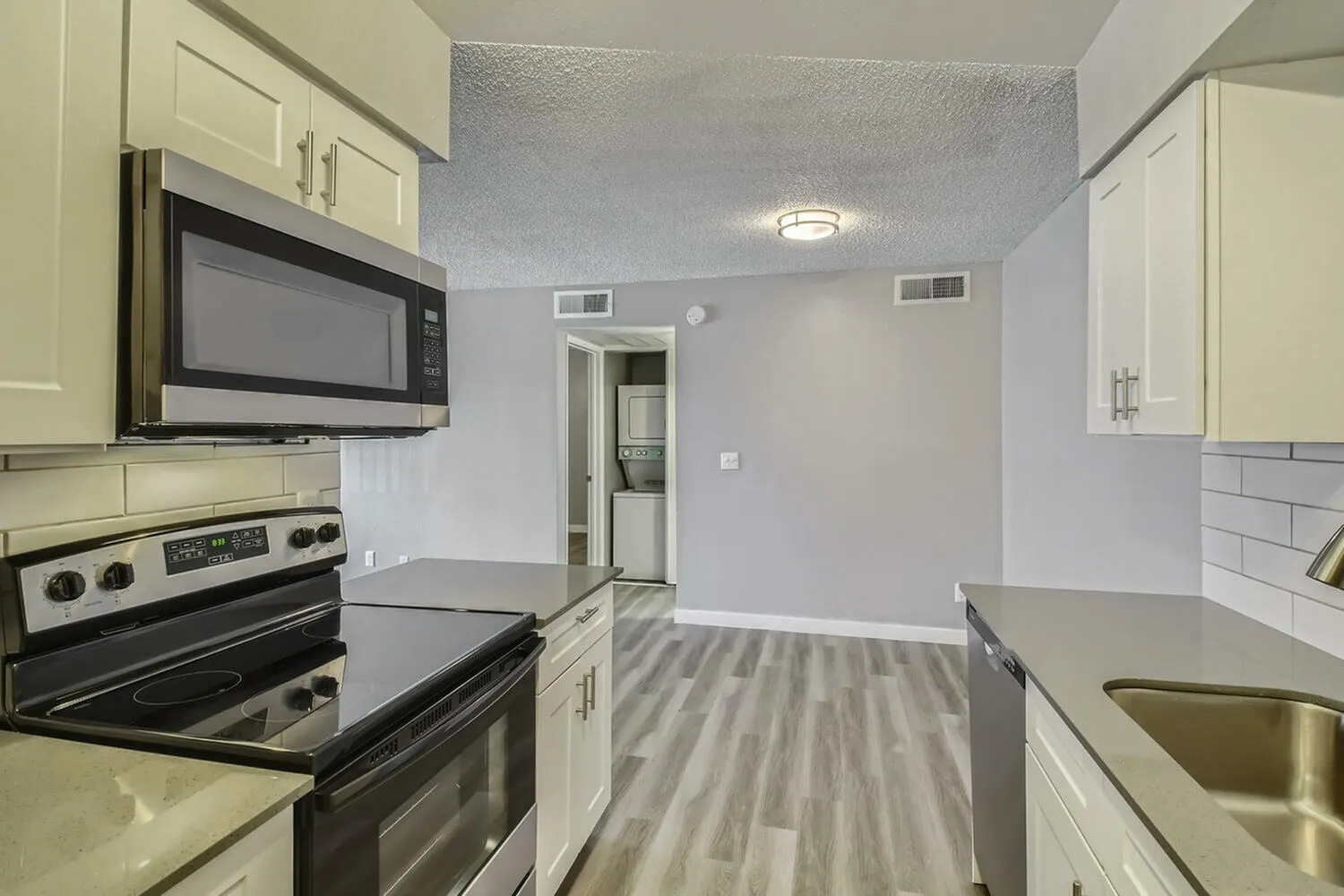 Kitchen, cream cabinetry, black stainless appliances, wood-style plank flooring, quartz countertops