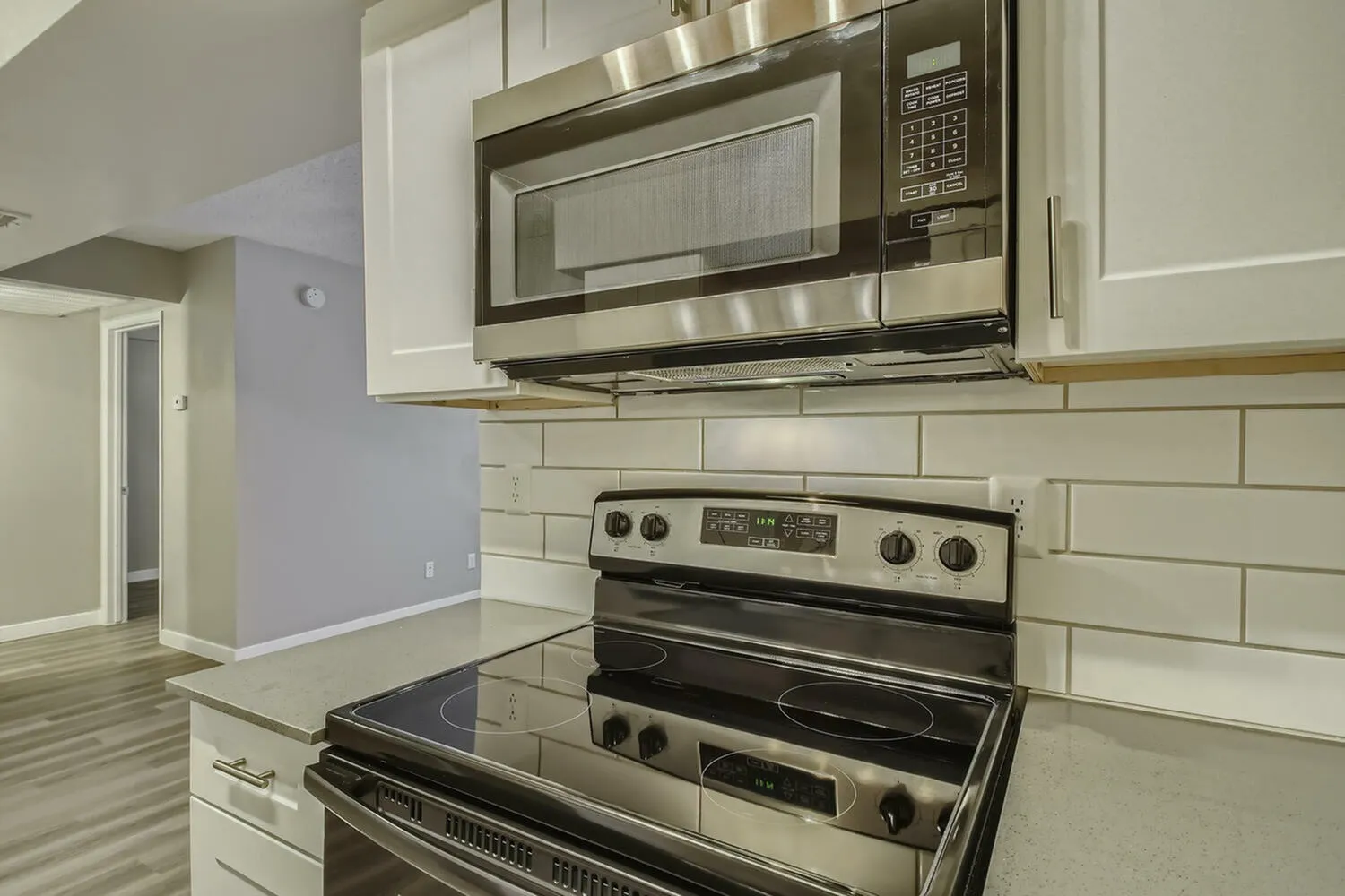 Kitchen, white shaker cabinetry, stainless steel appliances, subway tile backsplash, wood-style plank flooring