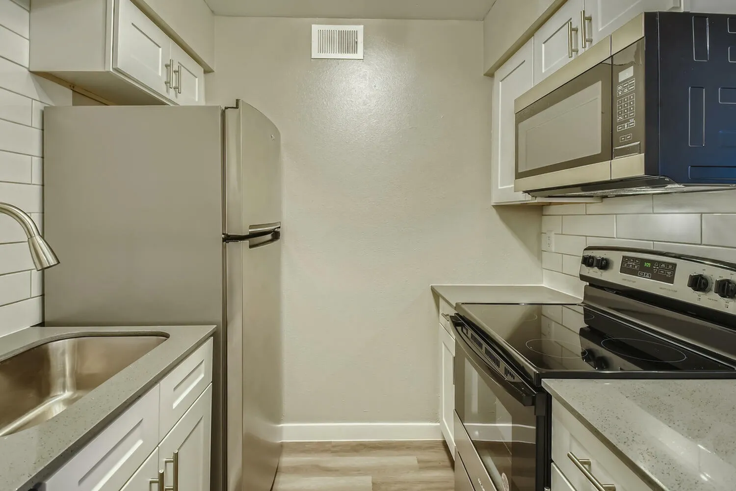 Kitchen, white shaker cabinetry, quartz countertops, stainless steel appliances, wood-style plank flooring