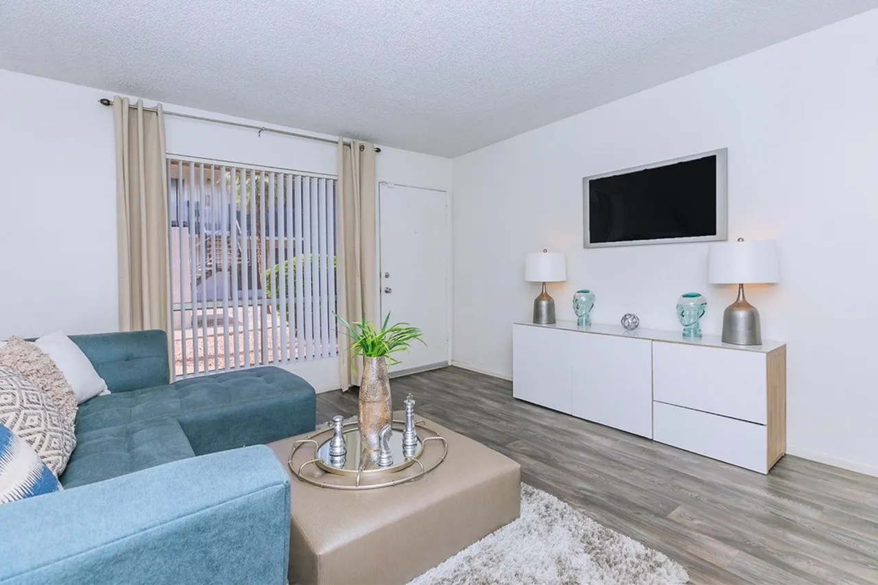 Living room, wood-style plank flooring, light blue sofa, wall-mounted TV, white cabinetry