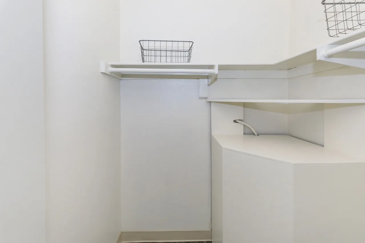 Walk-in closet, white shelving, wire basket organizers, white walls