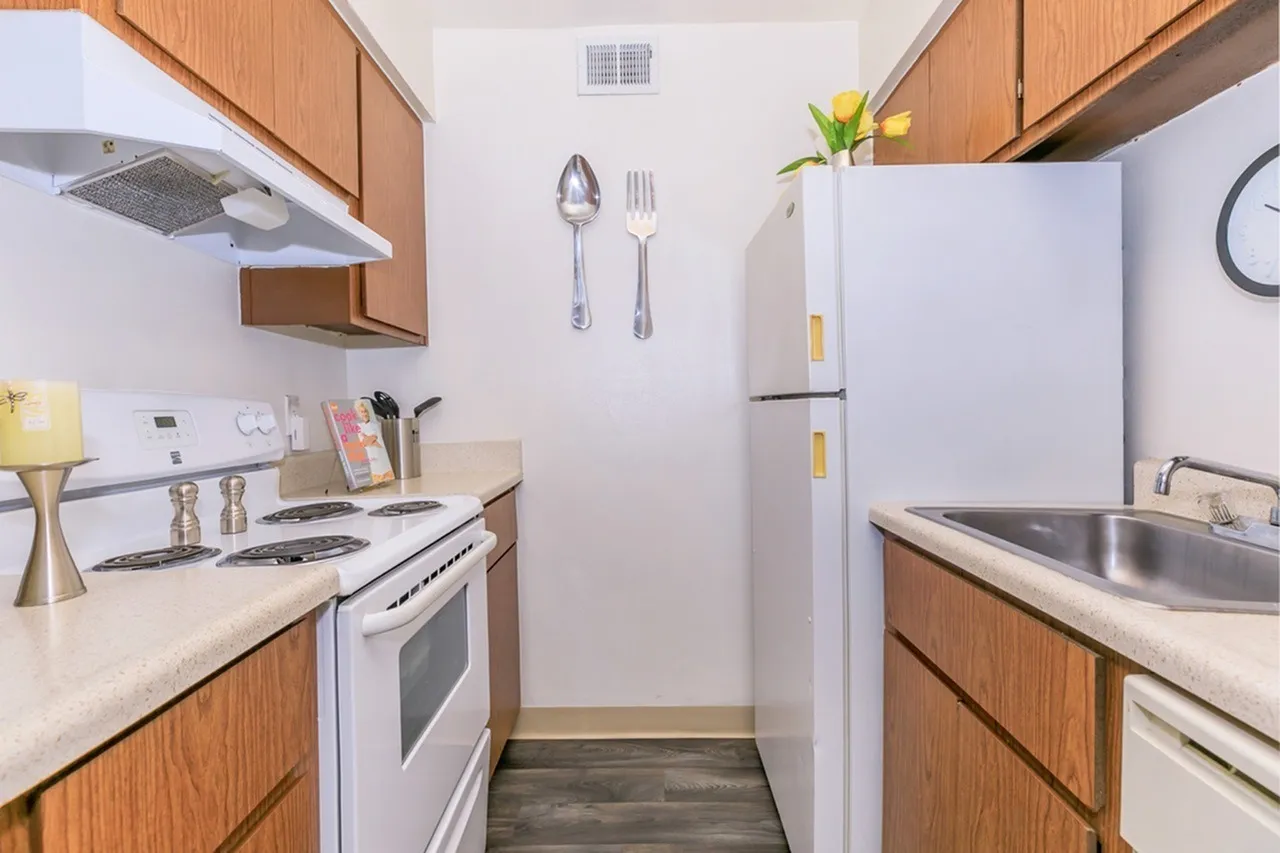 Kitchen, wood cabinetry, white appliances, white countertops, wood-style plank flooring