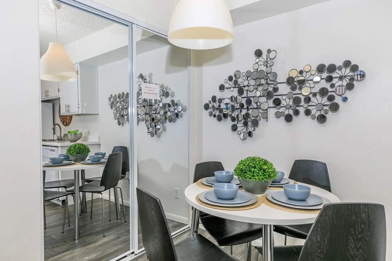 Dining room, wood-style plank flooring, black chairs, decorative circular mirrors