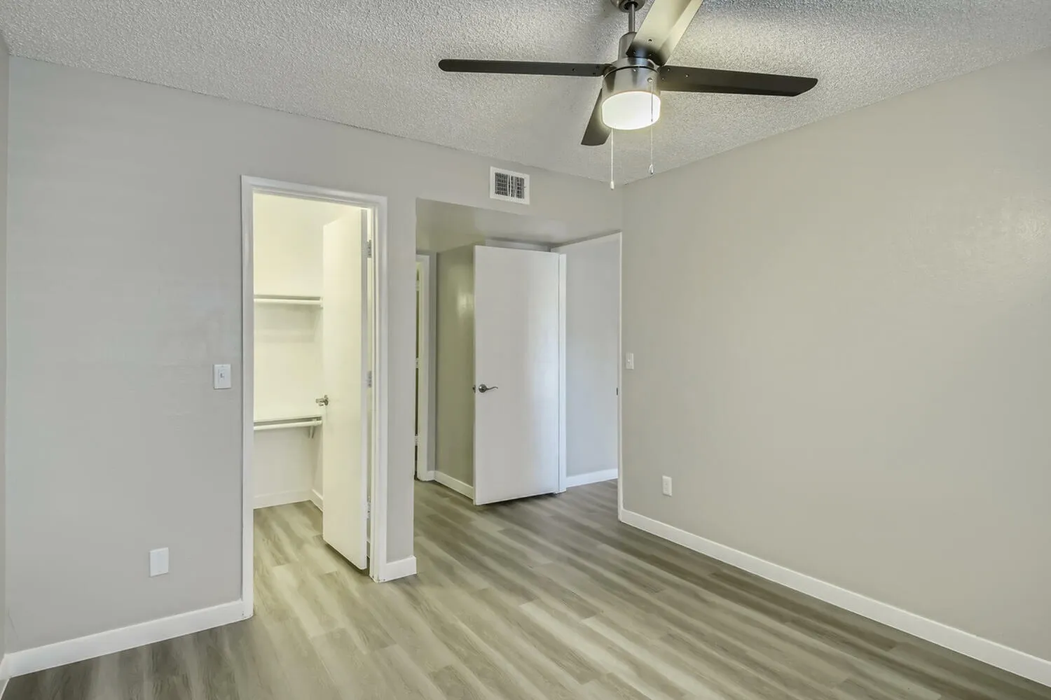 Primary bedroom, wood-style plank flooring, ceiling fan, walk-in closet, ensuite bathroom