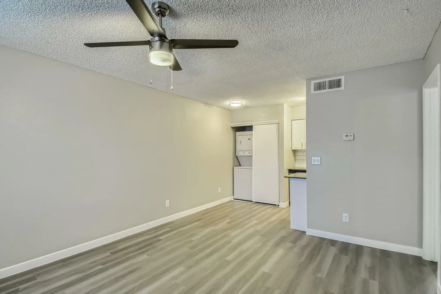Studio apartment, wood-style plank flooring, ceiling fan with light, kitchenette