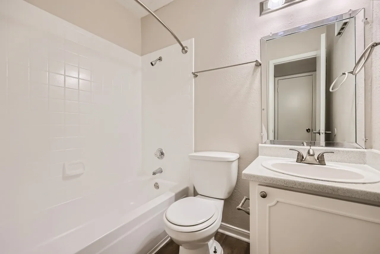 Primary bathroom, white subway tile shower surround, white vanity with quartz countertop, framed mirror