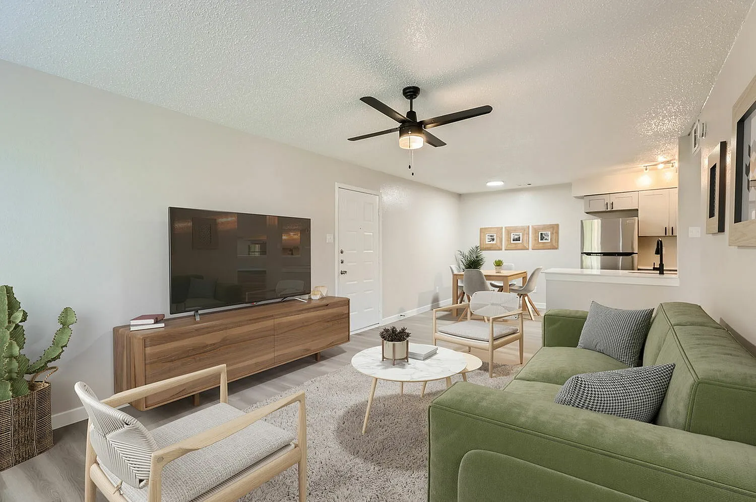 Living room with green sofa, wood-style plank flooring, ceiling fan, white accent chair