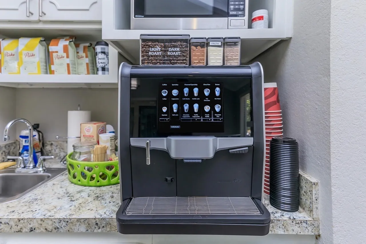 Kitchen, speckled quartz countertops, black automatic coffee machine, stainless steel microwave, open shelving