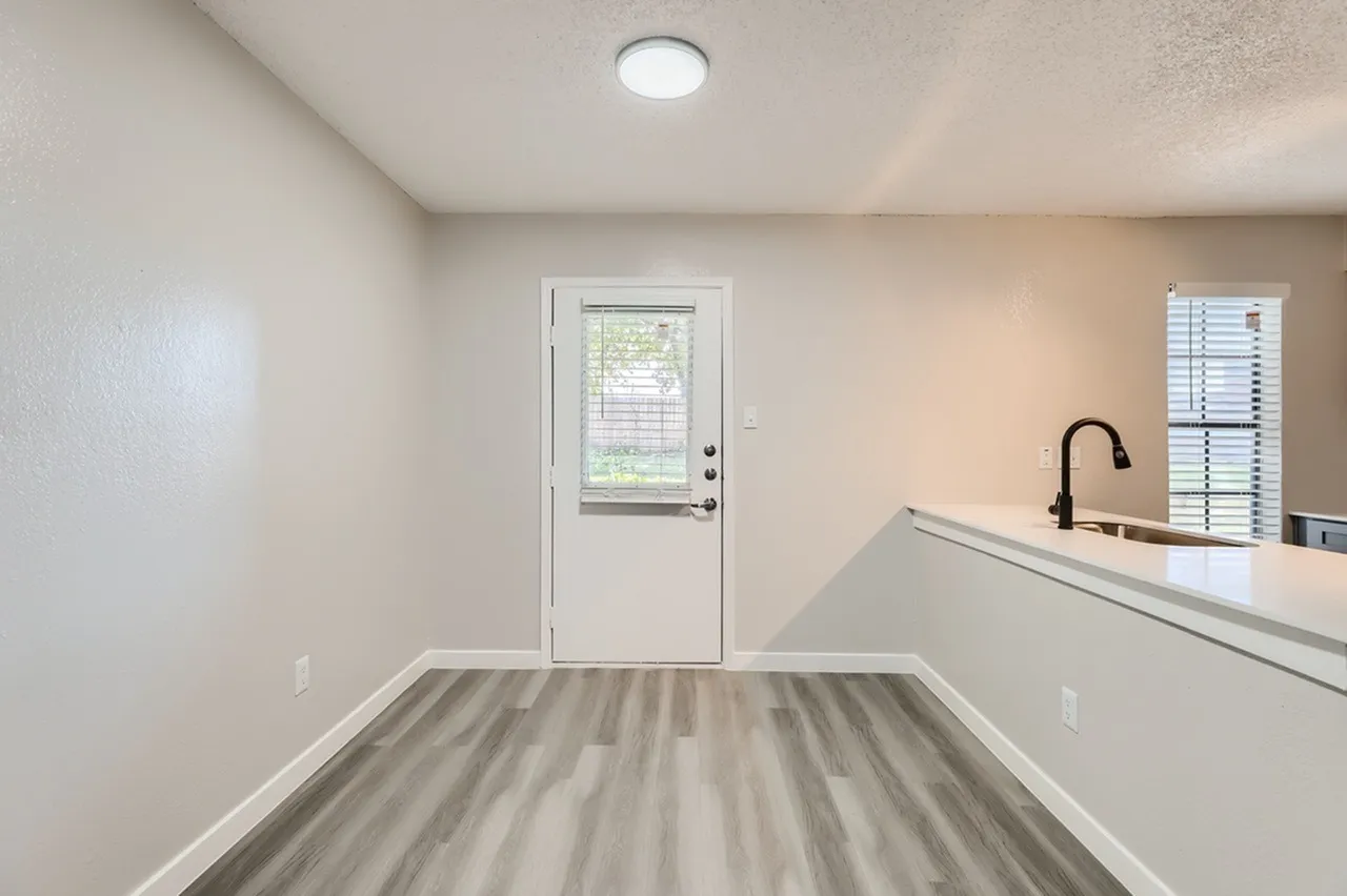 Utility room, wood-style plank flooring, sink with faucet, exterior door with window