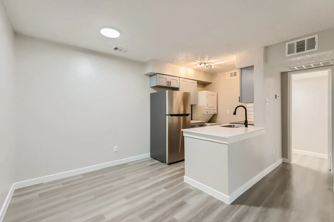 Kitchen with white island and quartz countertop, stainless steel refrigerator, wood-style plank flooring, recessed lighting