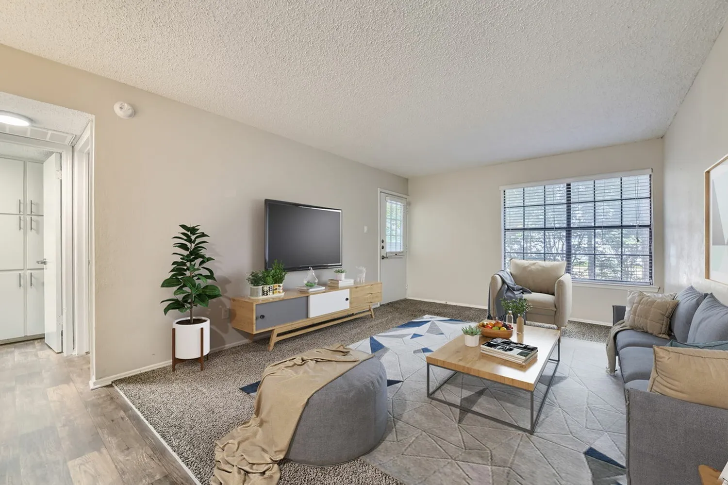 Living room, wood-style plank flooring, gray seating, wall-mounted TV, large windows