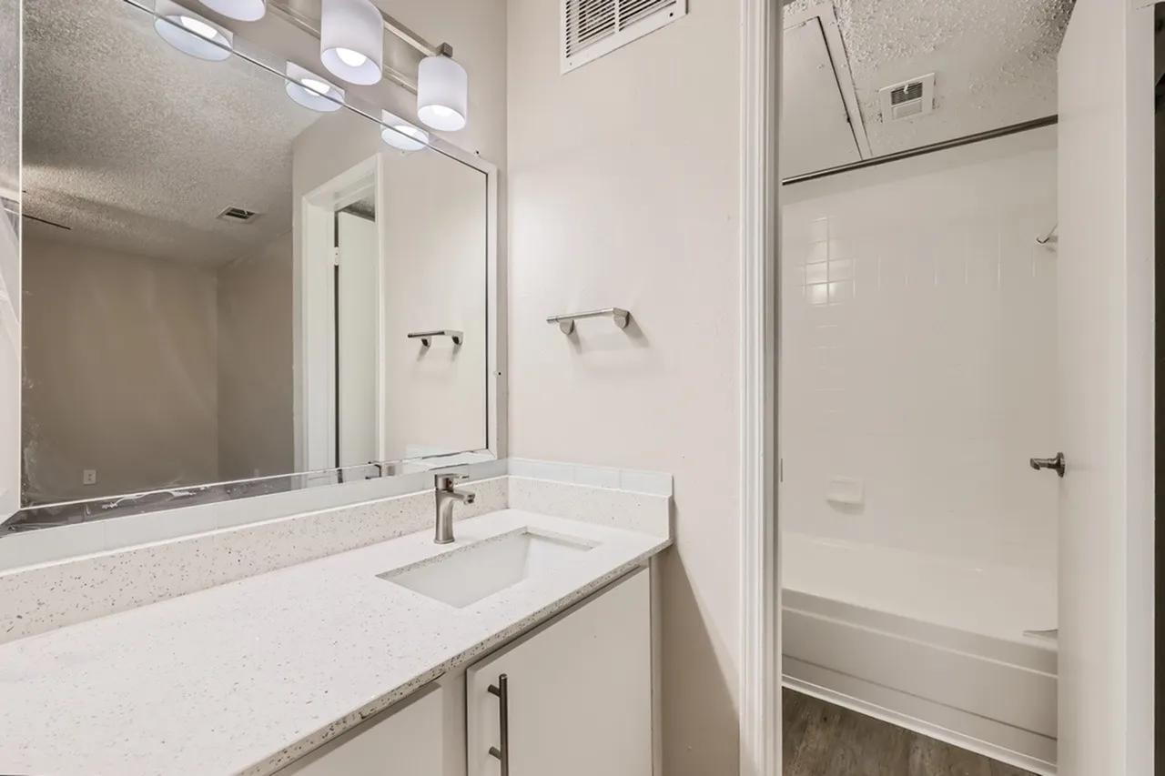 Primary bathroom, quartz countertops, single vanity sink, large mirror, shower enclosure
