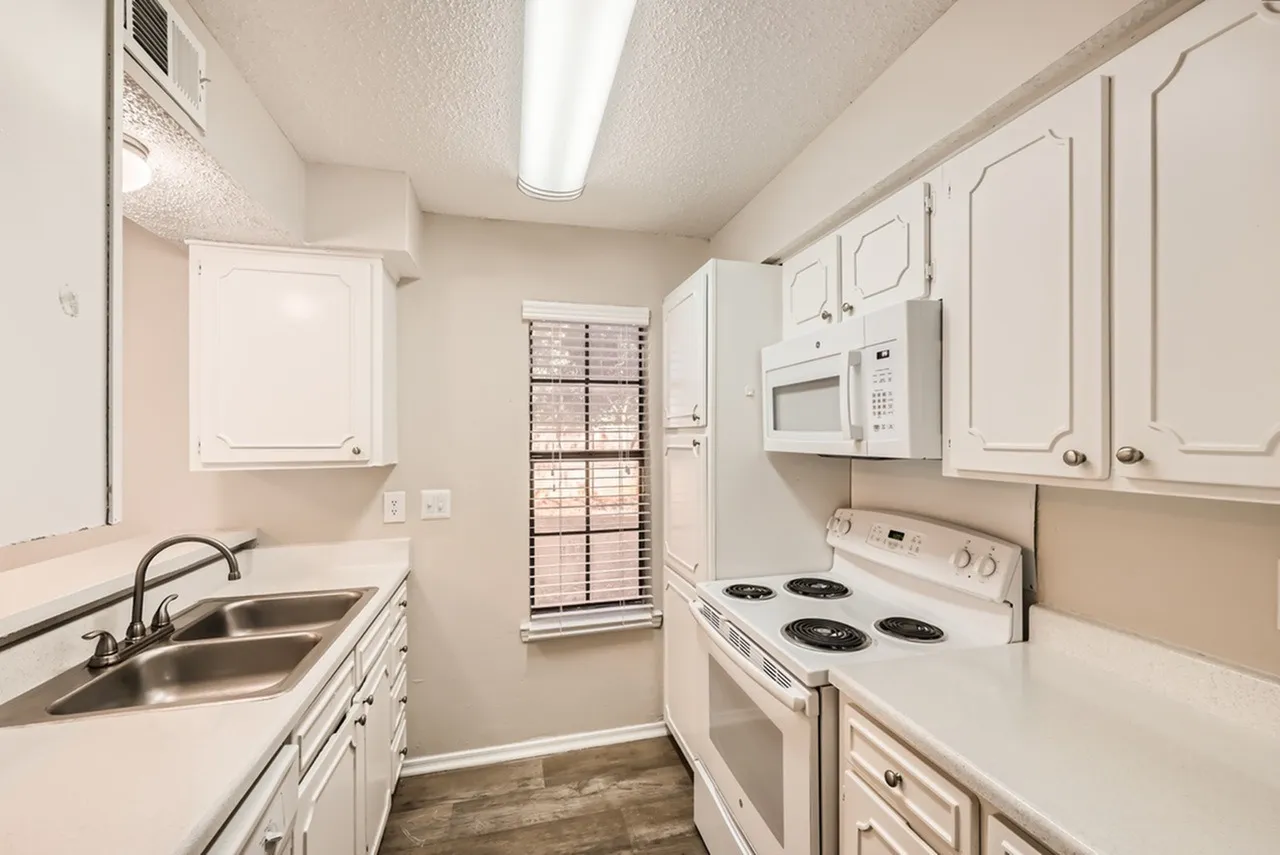 Kitchen, white cabinetry, stainless appliances, white countertops, wood-style plank flooring