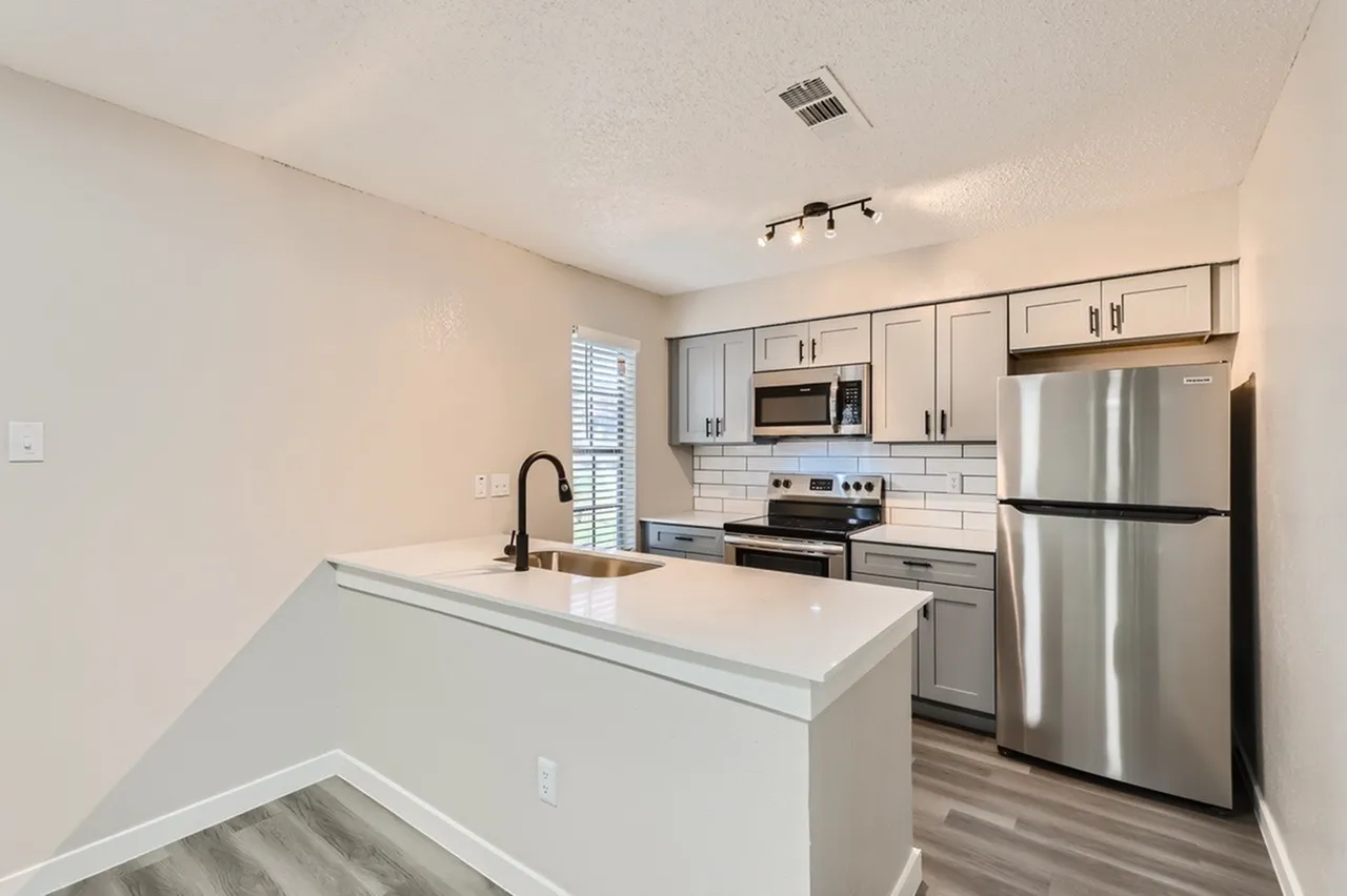 Kitchen, white quartz island countertop, gray shaker cabinetry, stainless appliances, wood-style plank flooring