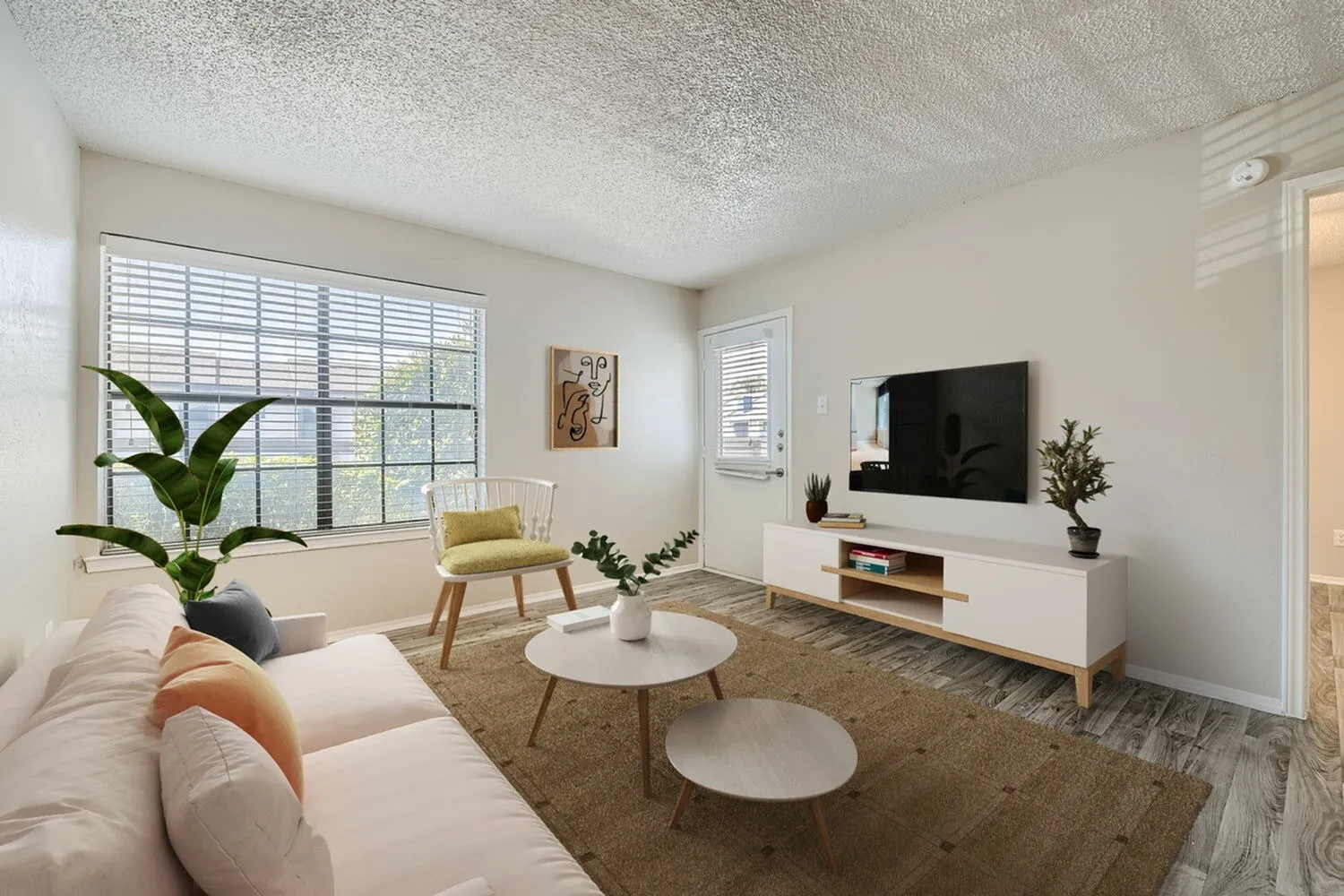 Living room, cream sofa, wood-style plank flooring, mounted television, round coffee table