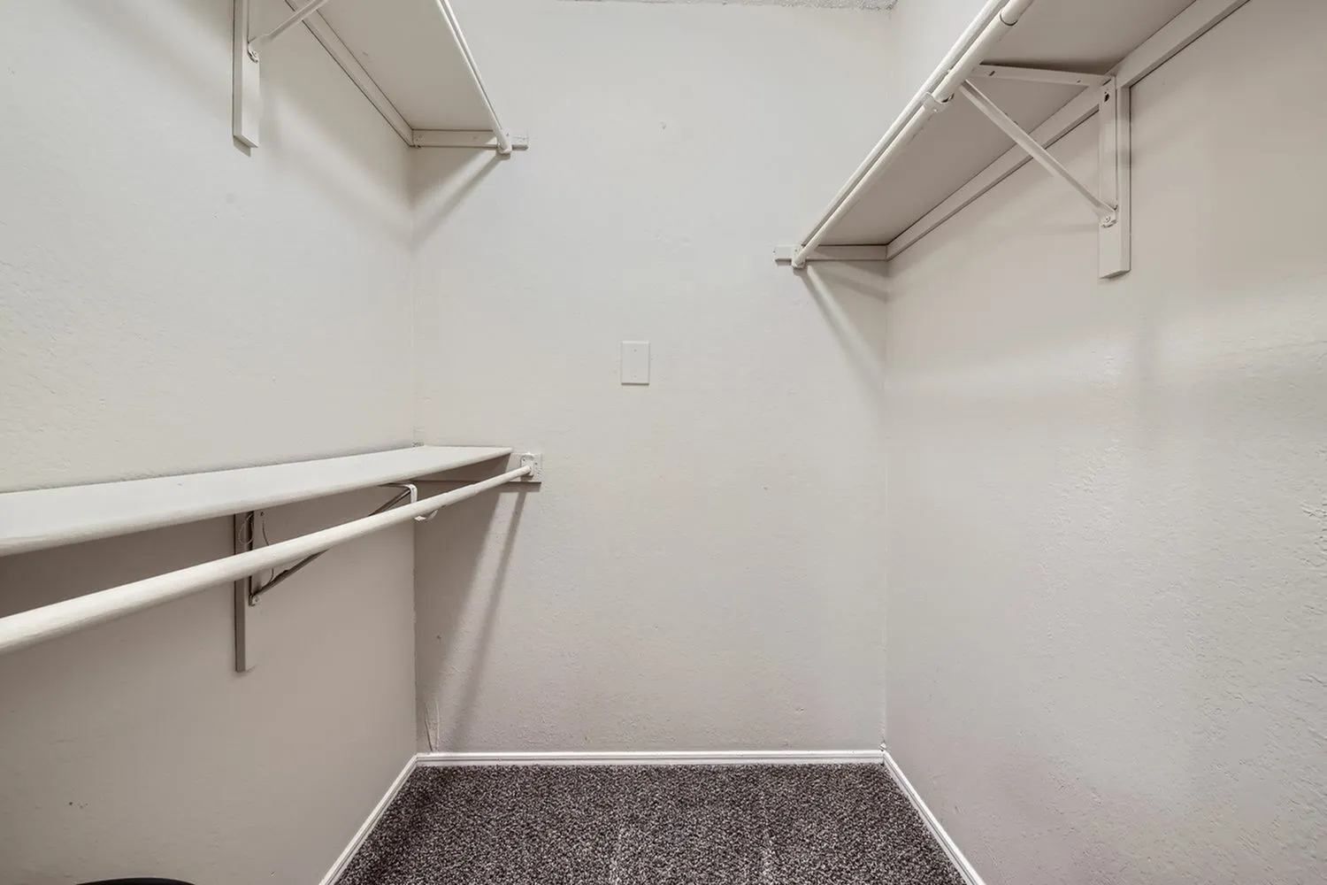 Walk-in closet, metal hanging rods, carpet flooring, wall-mounted shelving