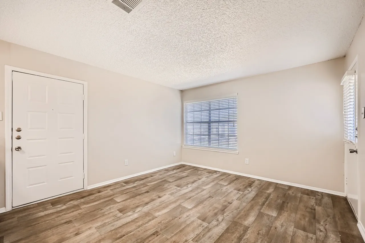 Bedroom, wood-style plank flooring, white entry door, window with shutters