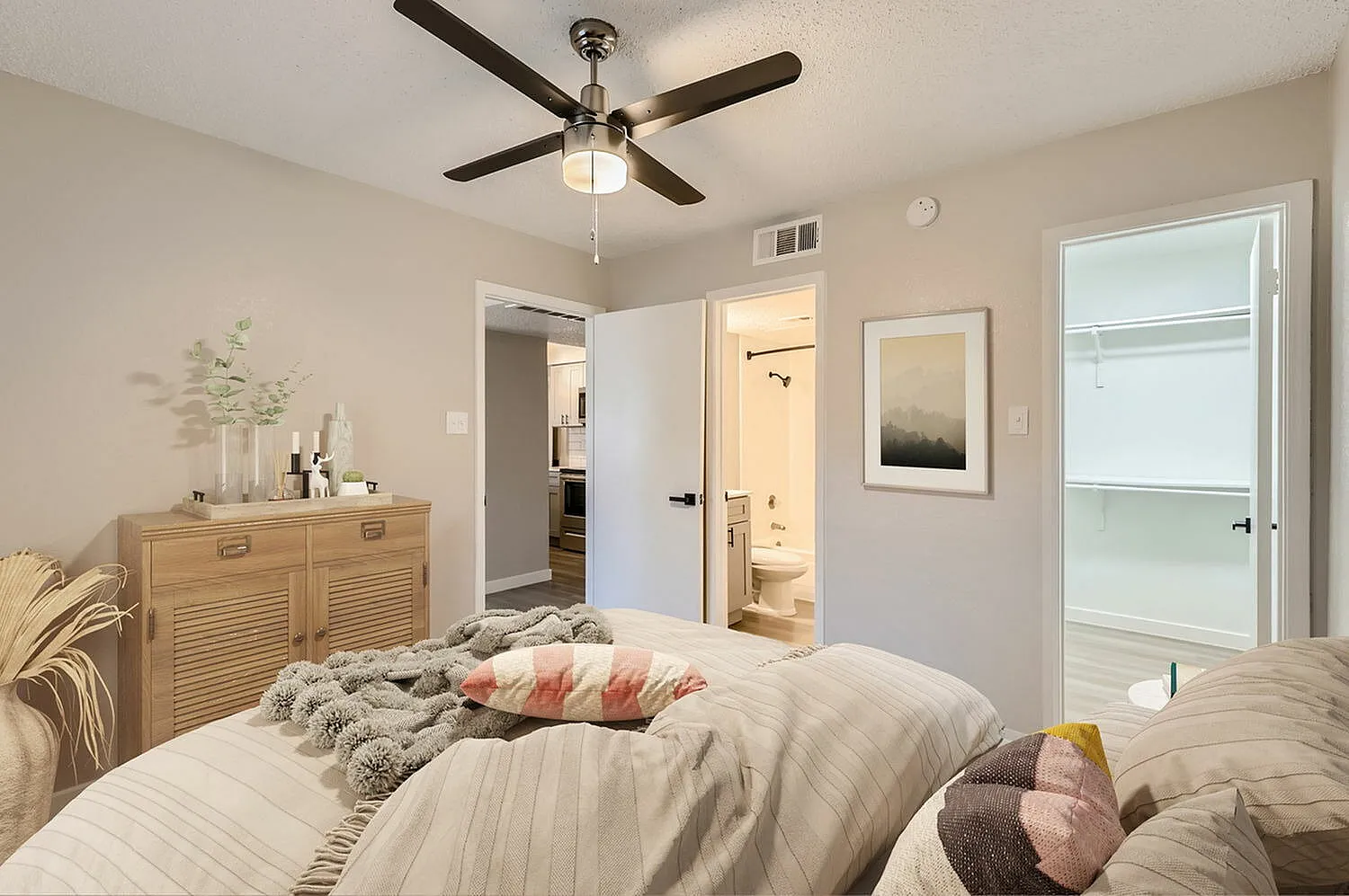 Primary bedroom, wood-style plank flooring, ceiling fan with light, ensuite bathroom access