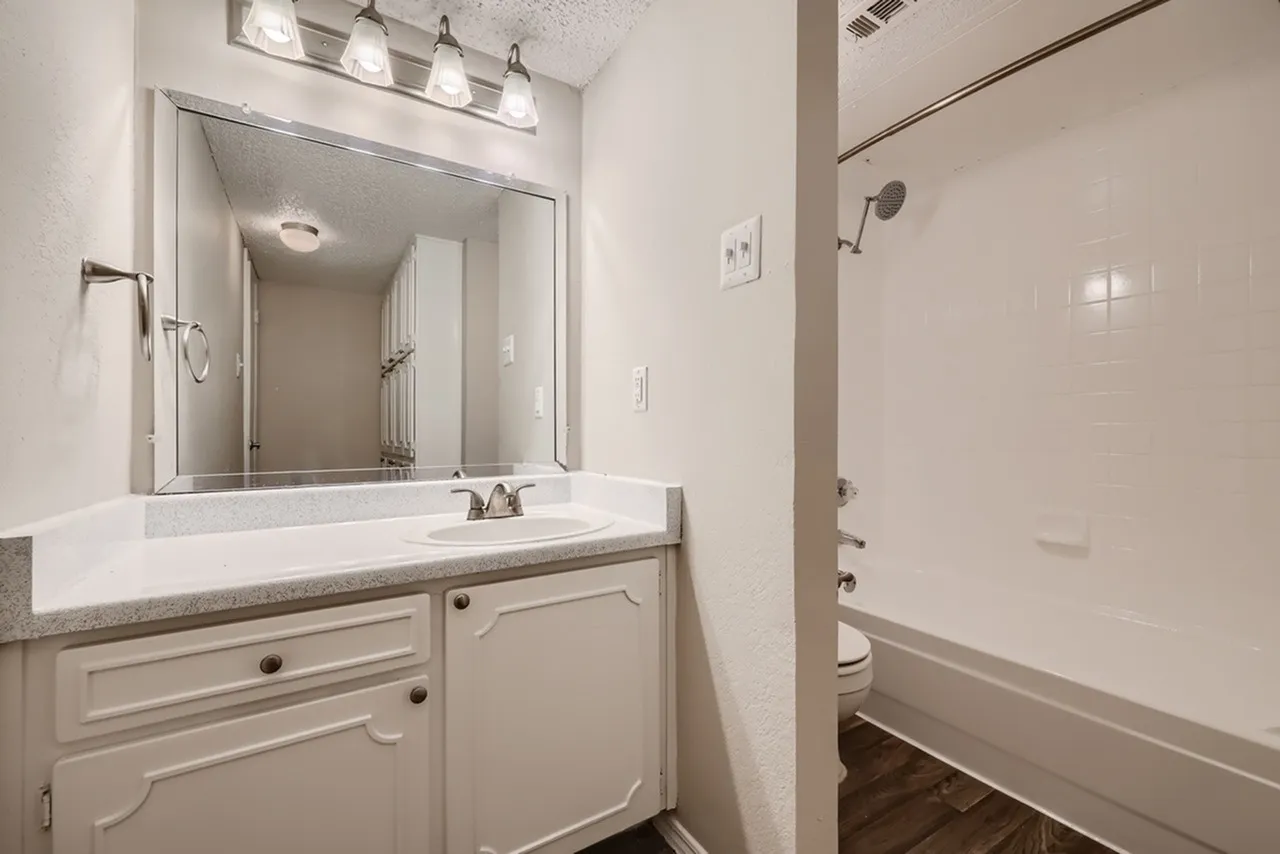 Primary bathroom, white vanity cabinetry, quartz countertops, framed mirror, pendant lighting