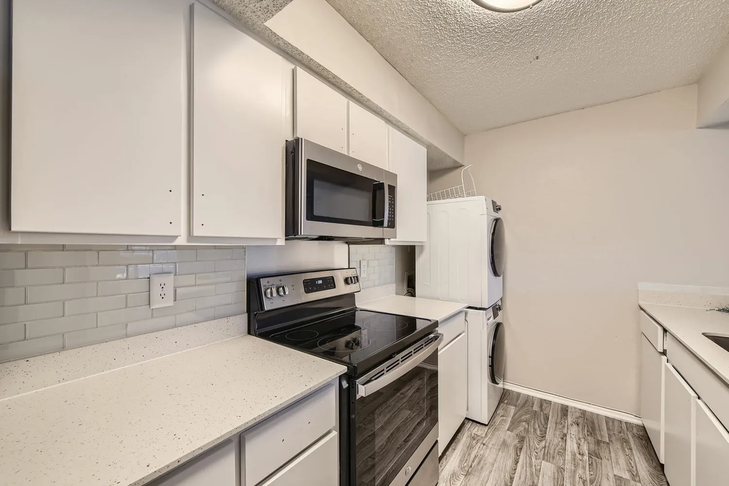 Kitchen, white shaker cabinetry, quartz countertops, stainless appliances, gray subway tile backsplash, wood-style plank flooring