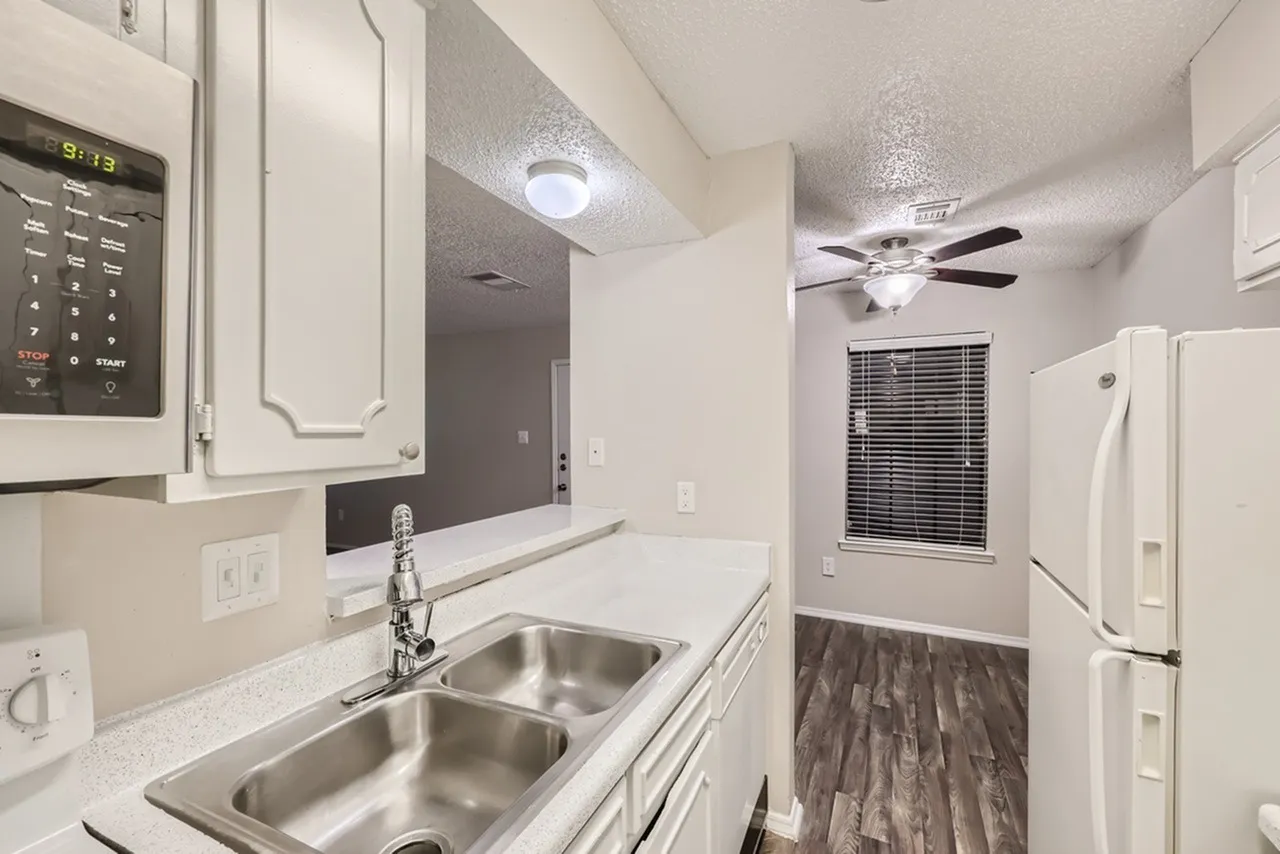 Kitchen, white shaker cabinetry, quartz countertops, stainless steel sink, wood-style plank flooring, ceiling fan
