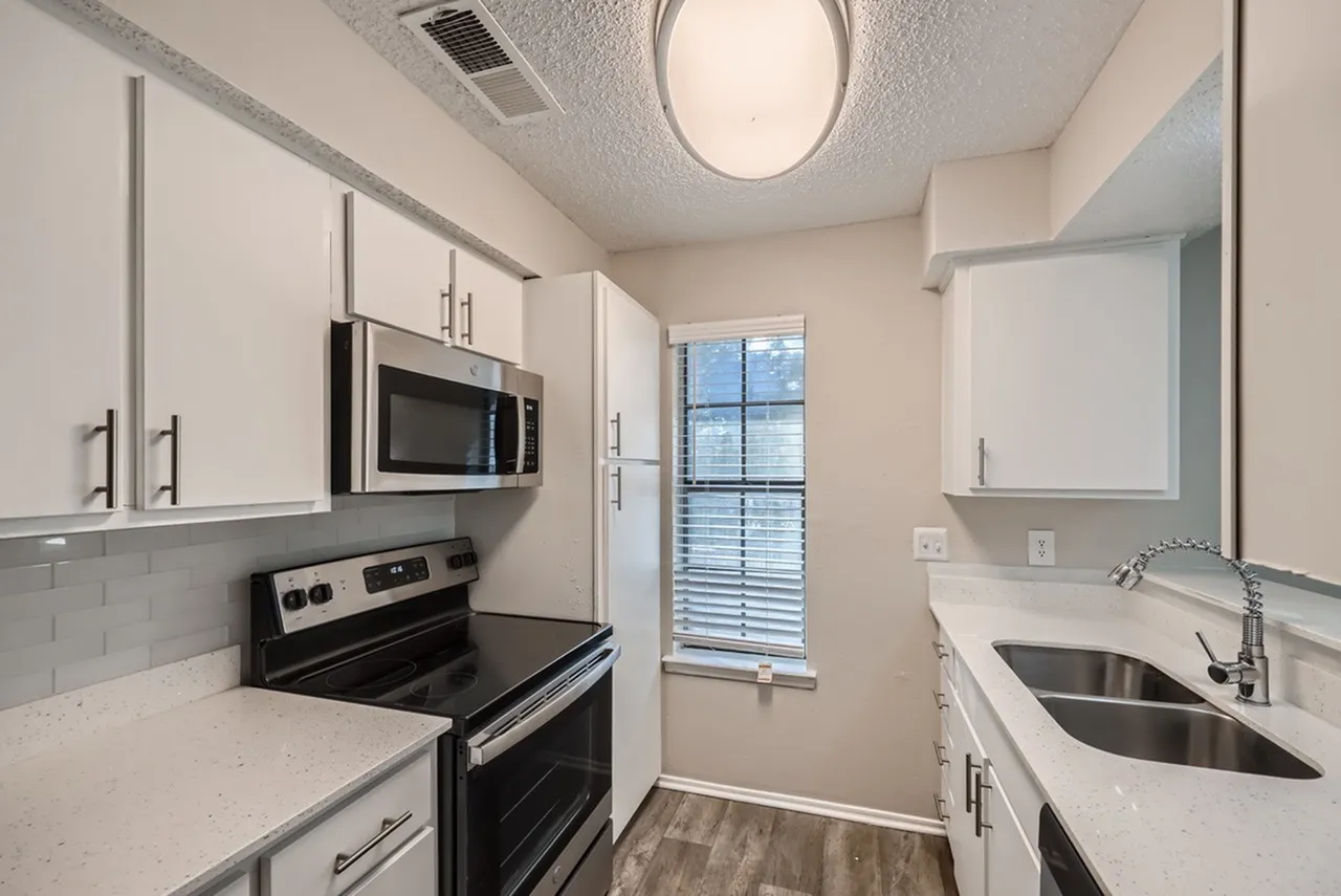 Kitchen, white shaker cabinetry, black stainless appliances, quartz countertops, wood-style plank flooring