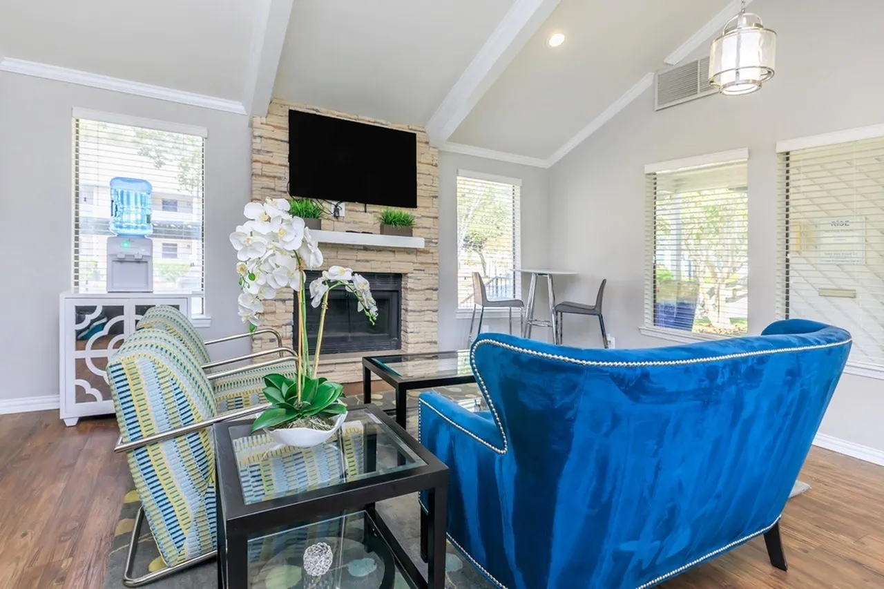 Living room, wood-style plank flooring, blue sofa, striped accent chair, fireplace with mounted TV
