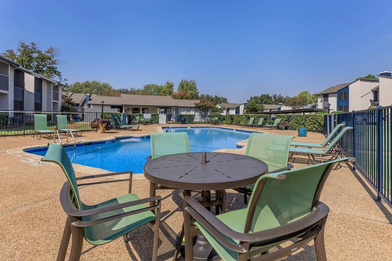 Community pool, lounge seating, round dining table, surrounding landscaping