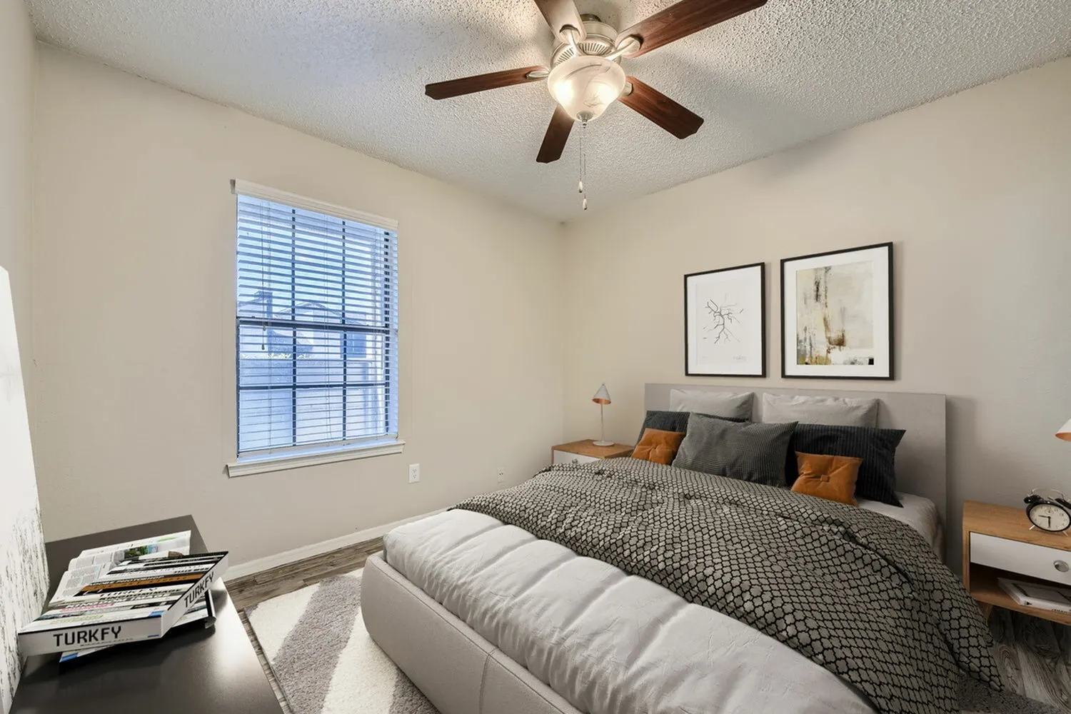 Primary bedroom, wood-style plank flooring, gray upholstered bed, ceiling fan with light