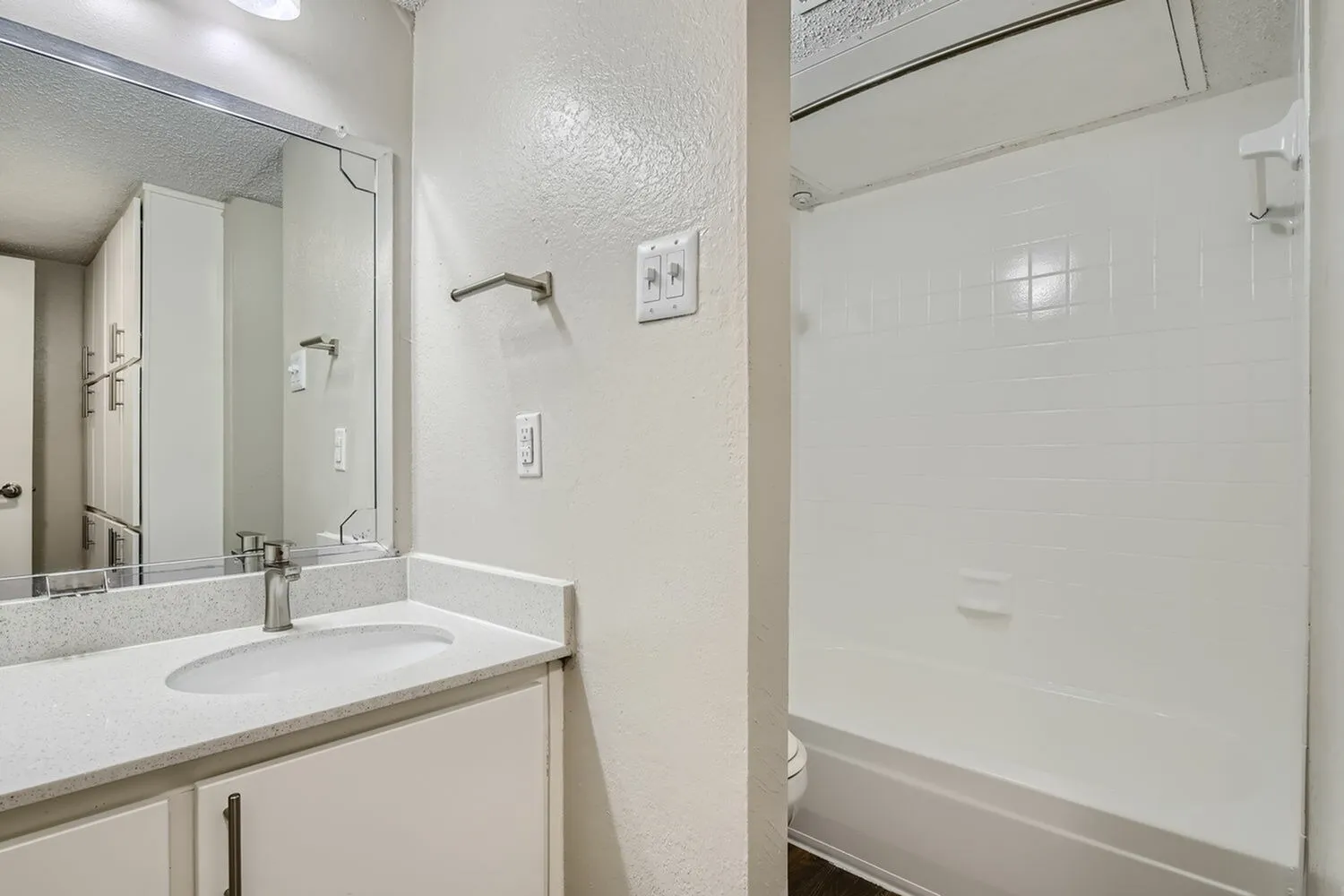 Bathroom, white vanity cabinetry, quartz countertop, framed mirror, glass shower enclosure