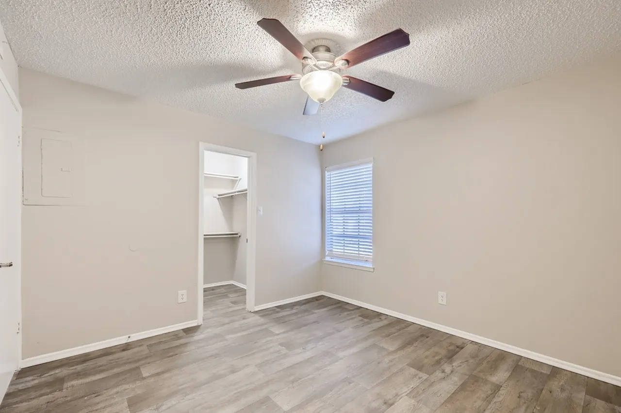 Bedroom, wood-style plank flooring, ceiling fan, window with blinds, built-in shelving