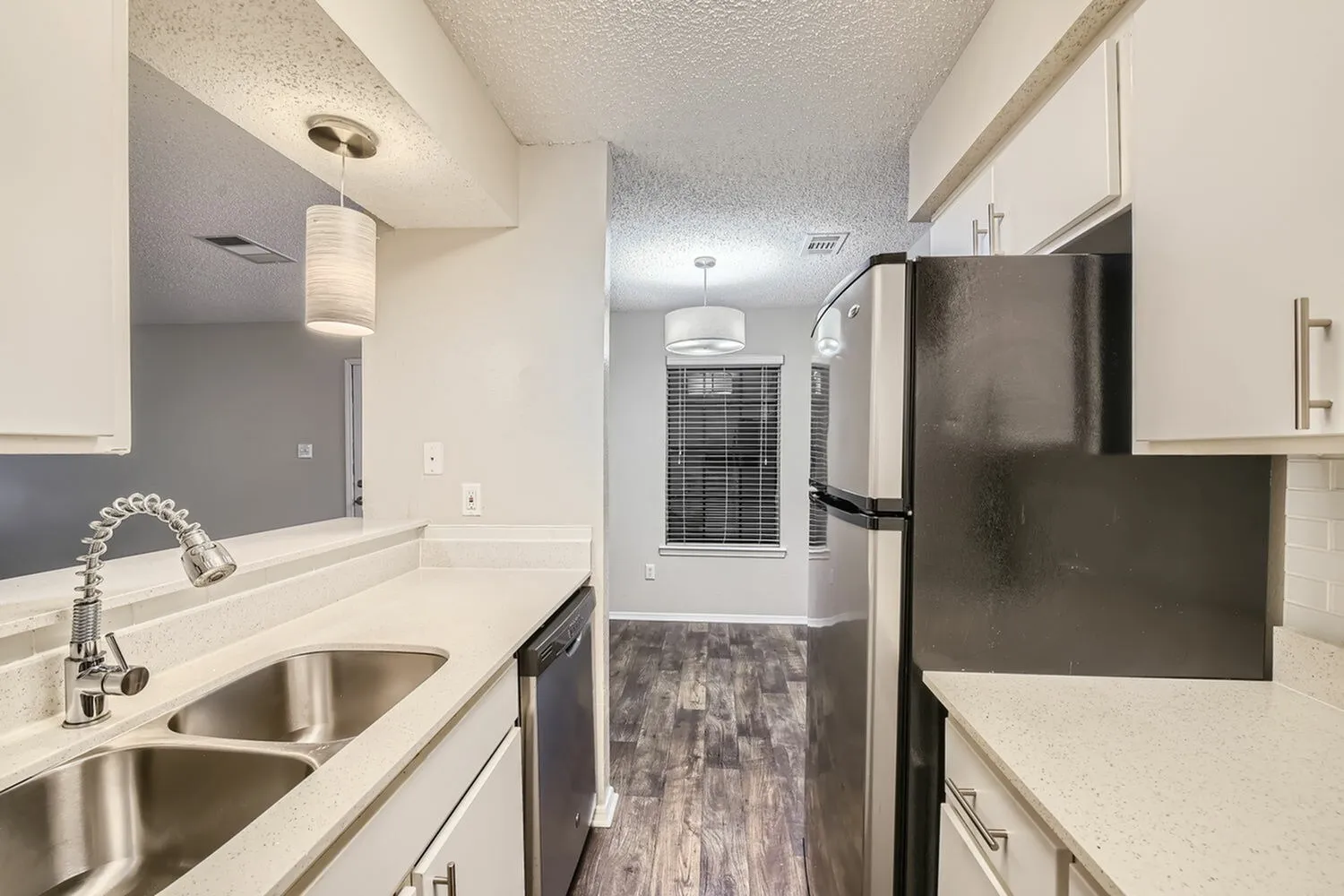 Kitchen with white cabinetry, quartz countertops, stainless steel dual sink, stainless appliances, wood-style plank flooring