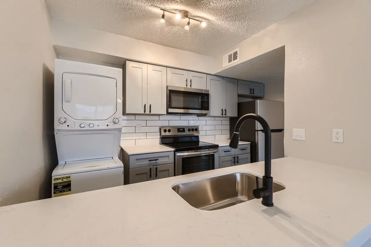 Kitchen, white shaker cabinetry, quartz countertops, stainless steel appliances, stacked washer dryer