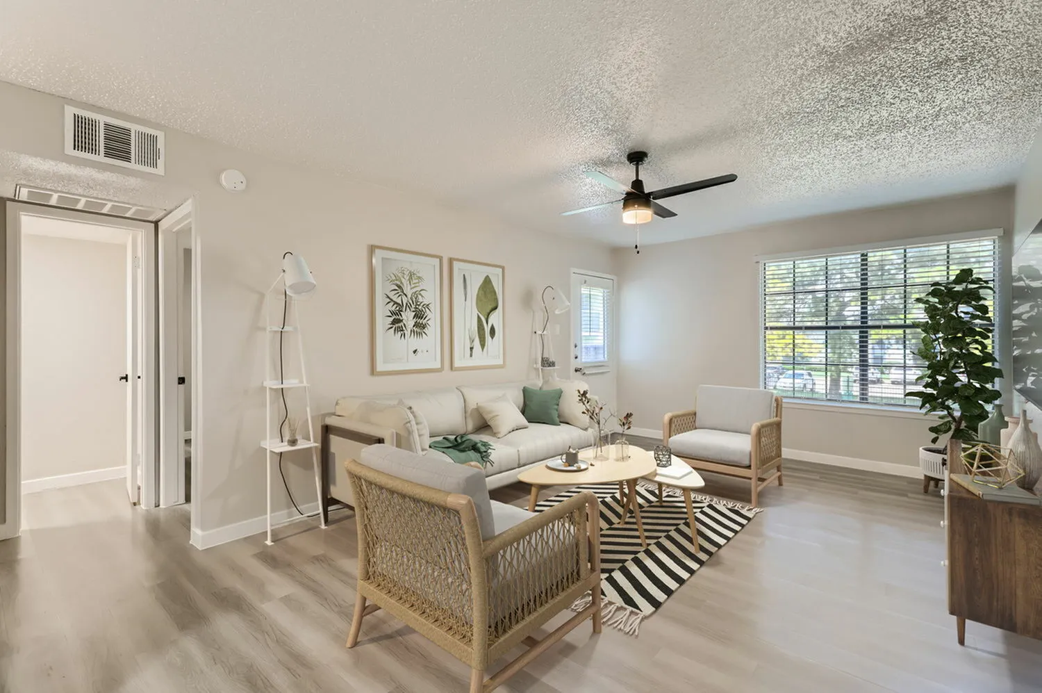 Living room, wood-style plank flooring, ceiling fan, upholstered sofa, woven accent chairs