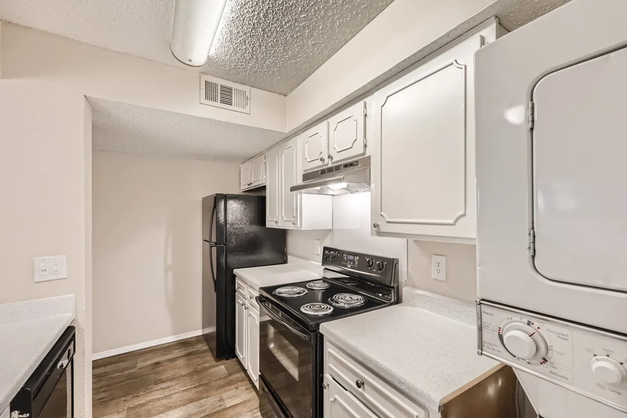 Kitchen, white cabinetry, black range, wood-style plank flooring, washer dryer
